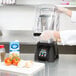 A person using a Waring outer sound enclosure on a blender in a professional kitchen.