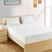A Bargoose Elite zippered queen mattress and boxspring cover on a bed with white sheets and pillows and a wooden frame.