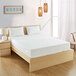 A Bargoose long full mattress encasement on a bed with white sheets and pillows and a wooden frame.