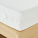 A white Bargoose Elite zippered mattress cover on a hospital twin mattress on a wooden bed.