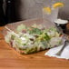 A salad in a Dart clear hinged plastic container on a table.