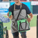 A man opening a Choice green insulated cooler bag filled with a brick cold pack.
