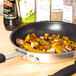A Carlisle non-stick fry pan with vegetables and spices in it.