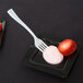 A Fineline white plastic tasting fork on a plate with a strawberry