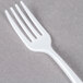 A white plastic Fineline Tiny Tines tasting fork.