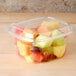 A Dart ClearPac plastic container filled with fruit with a yellow dome lid.