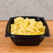 A Dart black plastic square bowl filled with macaroni and cheese.
