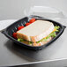 A sandwich with tomatoes and lettuce in a black Dart plastic bowl.