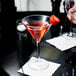 A close-up of a GET SAN Plastic Martini Glass with red liquid and a strawberry on top.