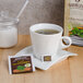 A white cup of Bromley Exotic Cool Mountain Mint herbal tea with a tea bag on a saucer.