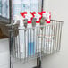 A Regency chrome storage basket holding plastic containers and spray bottles.