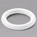 A white round rubber O-ring on a gray surface.