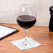 A Thunder Group plastic wine glass filled with red wine on a table.