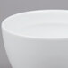 An Arcoroc white china cup with a small amount of liquid in it.