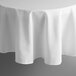 A white Intedge round cloth table cover with a hemmed edge on a table.
