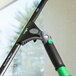 An Unger ErgoTec Ninja window cleaner with a green and black handle.