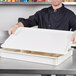 A man holding a white Cambro pizza dough proofing box lid with dough inside.