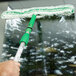 A hand using an Unger Monsoon Plus StripWasher with T-Bar to clean a window.