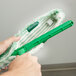 A hand holding a green Unger Monsoon Plus StripWasher with Plastic T-Bar.