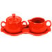 A red ceramic tray with a creamer and sugar bowl set.