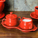 A red Fiesta sugar and creamer tray set on a wooden surface.