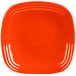 A close up of a red square plate with an orange rim.
