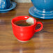 A red Fiesta china mug with a tea bag in it on a table.