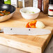 A Victorinox knife with a blade cover on a cutting board with vegetables.
