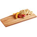 An American Metalcraft olive wood serving board with fruit and crackers on it.