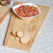 An American Metalcraft olive wood serving board with a bowl of salsa and slices of bread.