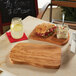 An American Metalcraft olive wood entree board with a sandwich and salad on a table.