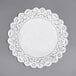A white paper Normandy lace doily with a white border on a gray surface.