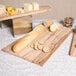 An American Metalcraft olive wood serving board with bread and cheese on it.