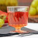 A clear Fineline plastic wine cup filled with red liquid on a white napkin.