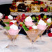 A row of Libbey mini martini glasses filled with pink and white desserts on a dessert table.