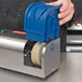 A person using the Edlund 401-230V Electric Knife Sharpener to sharpen a knife in a blue plastic container.