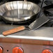 A Dexter-Russell solid turner with a wood handle being used to flip food in a pan on a stove.