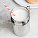 An American Metalcraft stainless steel milk can creamer with a straw in it.