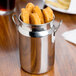 An American Metalcraft stainless steel milk can creamer on a table filled with fried chicken nuggets.