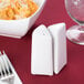 An American Metalcraft porcelain triangle salt and pepper shaker set on a table with food.