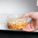 A hand holding a Solo clear plastic container of spaghetti.