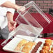 A person using a Cambro clear dome display cover to cover a tray of pastries.