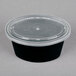 A clear oval plastic lid on a black souffle container.