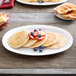 A white Thunder Group Nustone melamine platter with a stack of pancakes topped with strawberries.