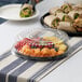 A Visions clear plastic catering tray with fruit and sandwiches on it on an outdoor table.