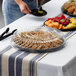 A clear Visions round catering tray with cookies and fruit on a table outdoors.