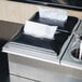 A Steril-Sil black and silver napkin dispenser on a metal surface.