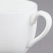 A close up of a CAC white European bone china cup with a handle.