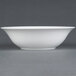 A close up of a white CAC Majesty European bone china salad bowl with a small rim on a gray surface.