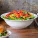 A CAC bone china salad bowl on a counter with salad and a sandwich.